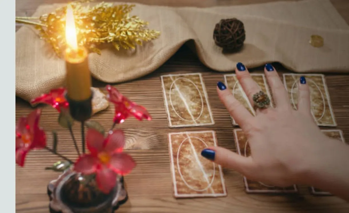 Mâini citind cărți tarot la lumânare